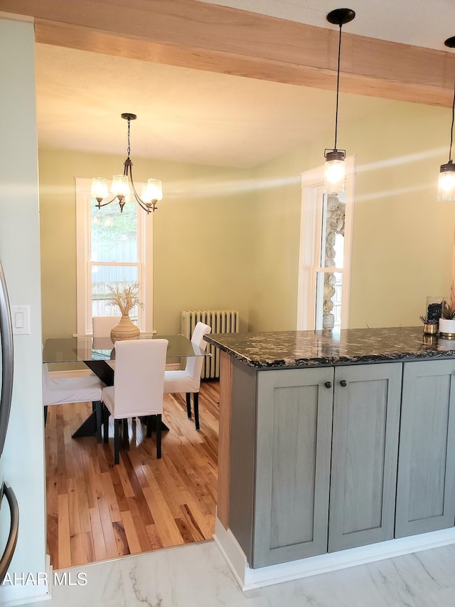 kitchen featuring beam ceiling, decorative light fixtures, an inviting chandelier, light hardwood / wood-style flooring, and radiator heating unit