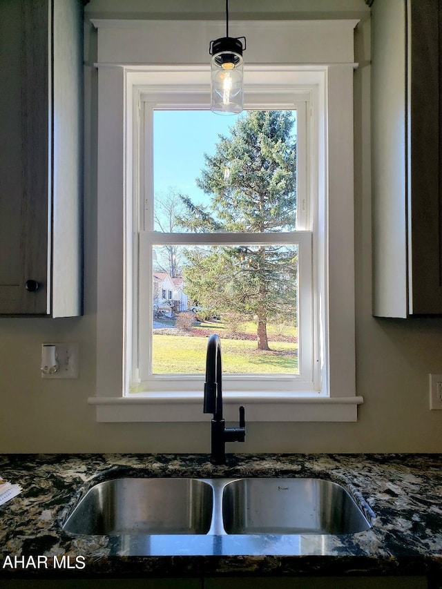 kitchen featuring hanging light fixtures, dark stone countertops, and sink