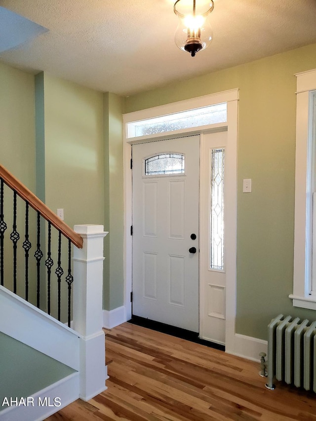 foyer featuring wood-type flooring, a textured ceiling, and radiator