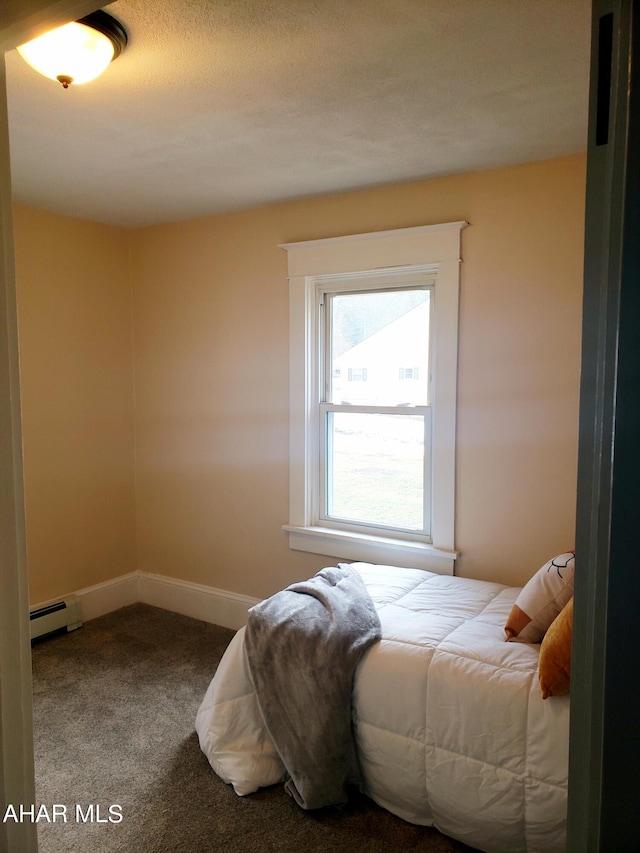 carpeted bedroom with a textured ceiling and a baseboard heating unit