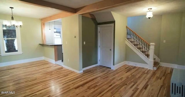 unfurnished room with beamed ceiling, hardwood / wood-style flooring, and an inviting chandelier