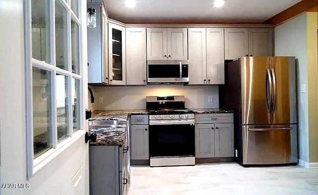 kitchen with gray cabinets, dark stone countertops, and stainless steel appliances