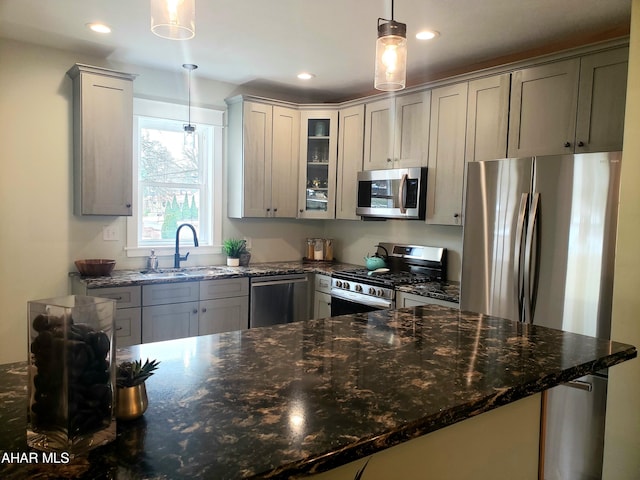 kitchen featuring dark stone counters, sink, gray cabinets, appliances with stainless steel finishes, and decorative light fixtures