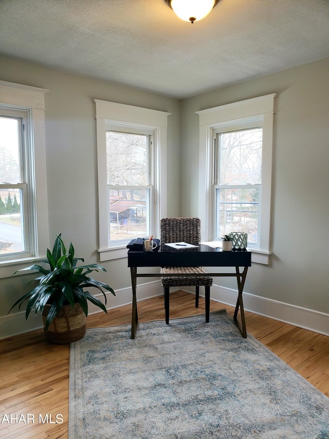 home office featuring wood-type flooring, a textured ceiling, and a wealth of natural light