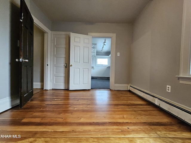 empty room featuring wood-type flooring and baseboard heating