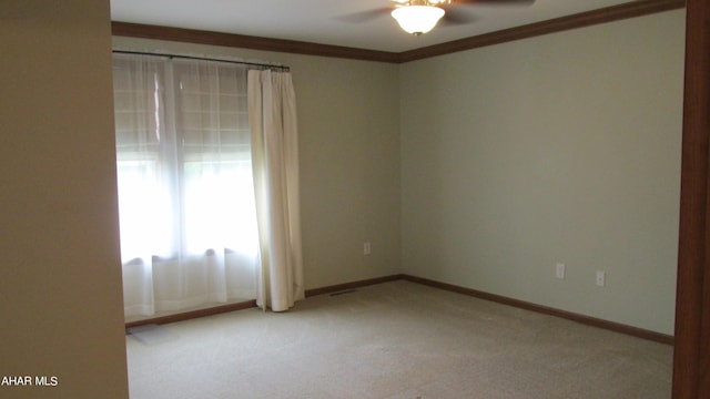 spare room with ceiling fan, crown molding, and light carpet