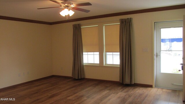 empty room featuring a wealth of natural light, crown molding, ceiling fan, and hardwood / wood-style flooring