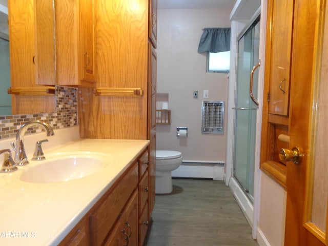 bathroom featuring toilet, a stall shower, a baseboard heating unit, tasteful backsplash, and vanity