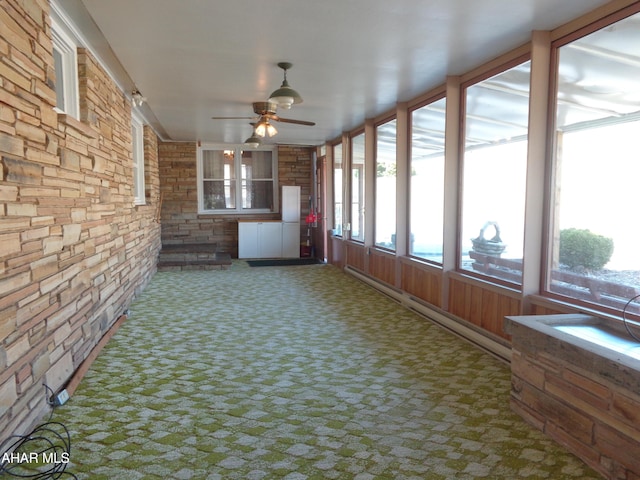 unfurnished sunroom with a ceiling fan and a baseboard radiator