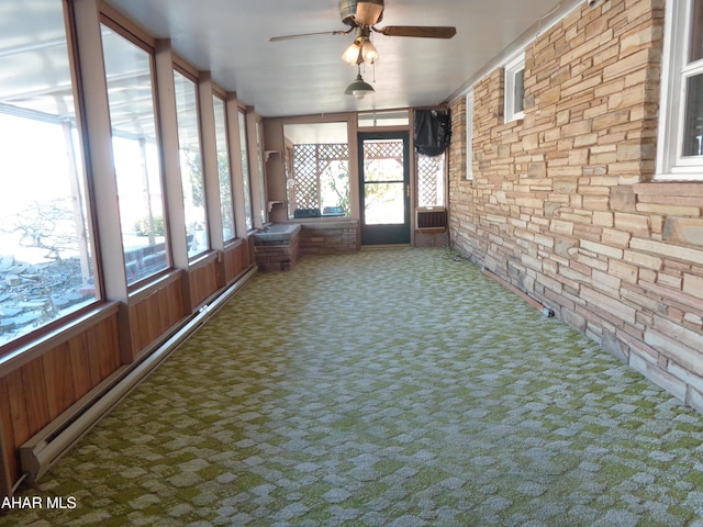 unfurnished sunroom featuring a baseboard heating unit, a wealth of natural light, and ceiling fan