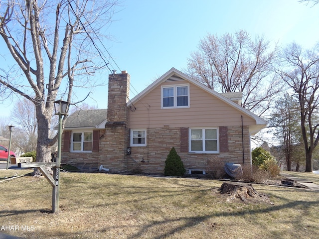 exterior space with stone siding, a chimney, a front lawn, and a shingled roof