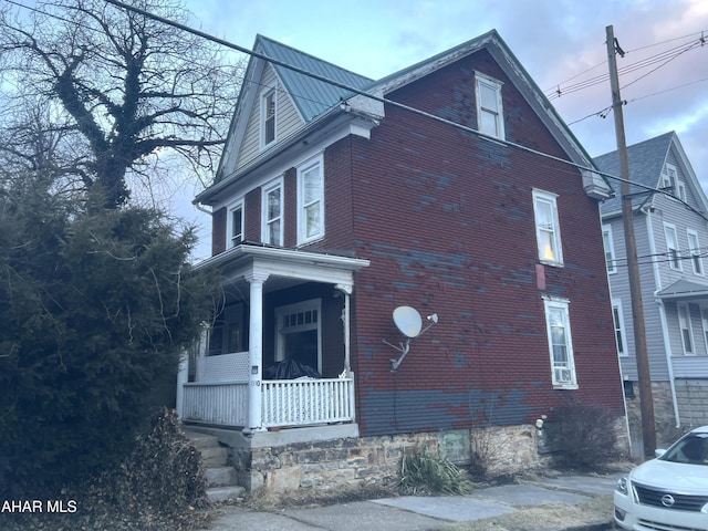 view of property exterior featuring metal roof, a porch, and brick siding