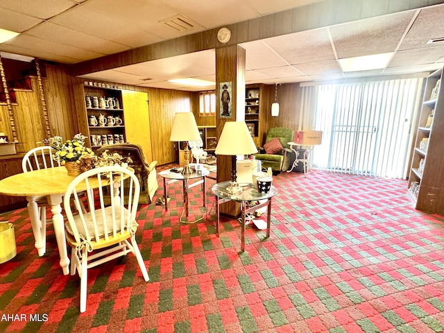 interior space with a drop ceiling, wooden walls, visible vents, and carpet