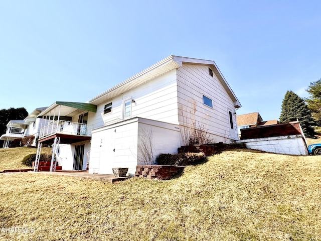 view of side of home with a balcony, a lawn, and a patio area