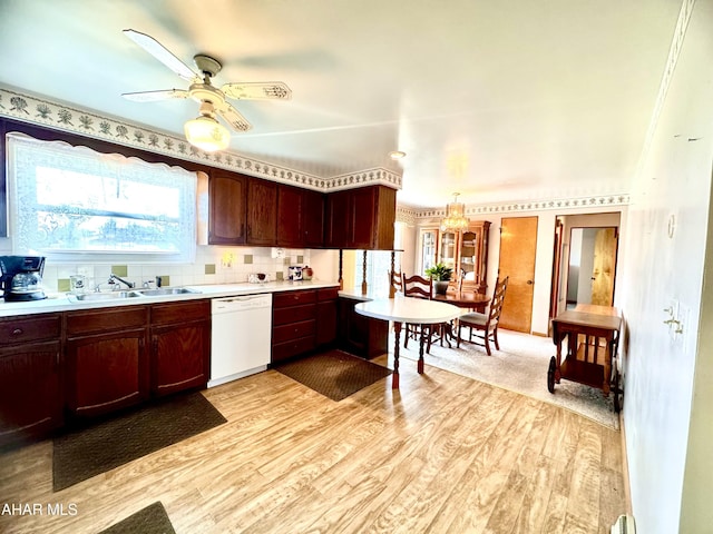 kitchen with light wood-type flooring, a sink, tasteful backsplash, light countertops, and dishwasher