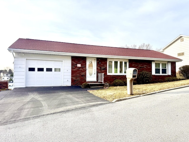 single story home featuring brick siding, an attached garage, a shingled roof, and driveway