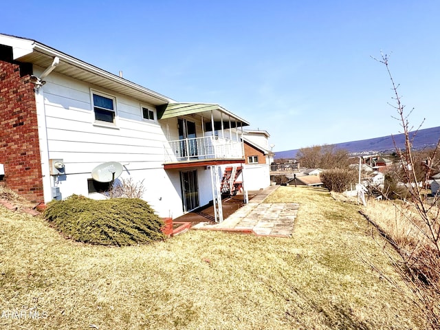 rear view of house featuring a balcony, brick siding, and a patio area