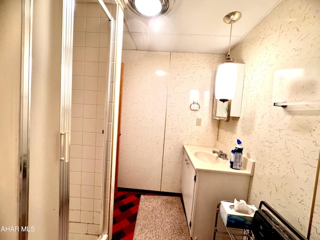 bathroom featuring vanity, a shower stall, and a textured wall