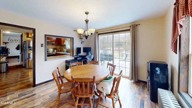 dining space with an inviting chandelier, radiator heating unit, wood finished floors, and baseboards