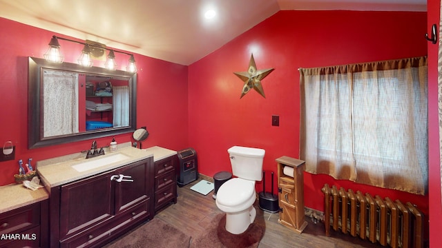 bathroom with radiator, toilet, vaulted ceiling, wood finished floors, and vanity