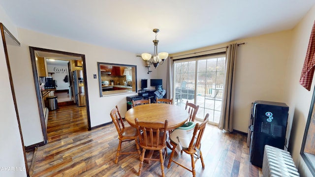 dining room featuring baseboards, wood-type flooring, a chandelier, and radiator heating unit