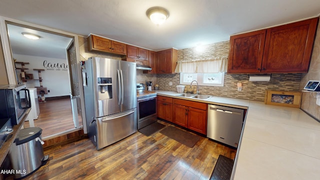 kitchen with dark wood-type flooring, a sink, tasteful backsplash, stainless steel appliances, and light countertops