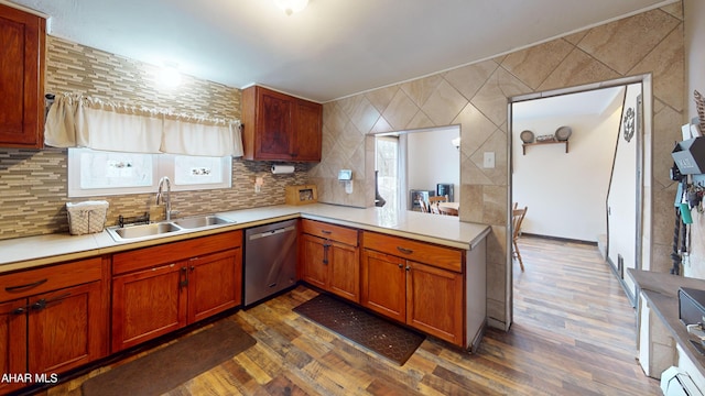 kitchen with a sink, dark wood-type flooring, stainless steel dishwasher, and light countertops