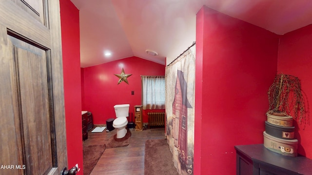 bathroom featuring toilet, radiator heating unit, lofted ceiling, and wood finished floors