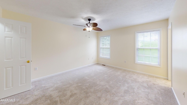 carpeted spare room with ceiling fan and baseboards
