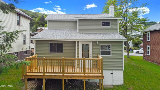 back of property with a yard and a wooden deck