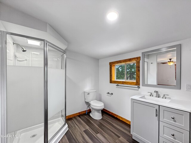 bathroom featuring ceiling fan, hardwood / wood-style floors, an enclosed shower, toilet, and vanity