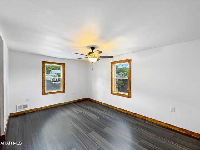 unfurnished room featuring ceiling fan, a healthy amount of sunlight, and dark hardwood / wood-style flooring