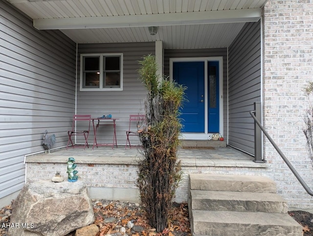 entrance to property with brick siding and a porch