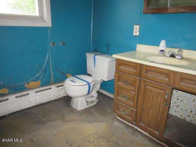 bathroom with toilet, vanity, and concrete floors