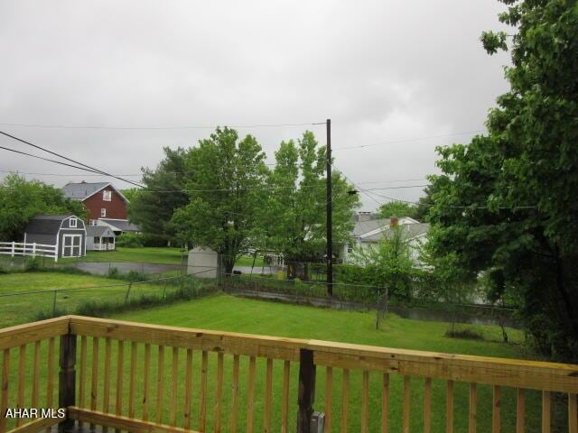 wooden terrace featuring a storage shed and an outbuilding