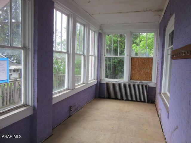 unfurnished sunroom featuring radiator heating unit
