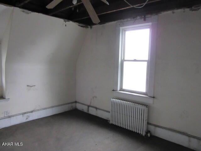 additional living space featuring radiator, plenty of natural light, a ceiling fan, and concrete flooring