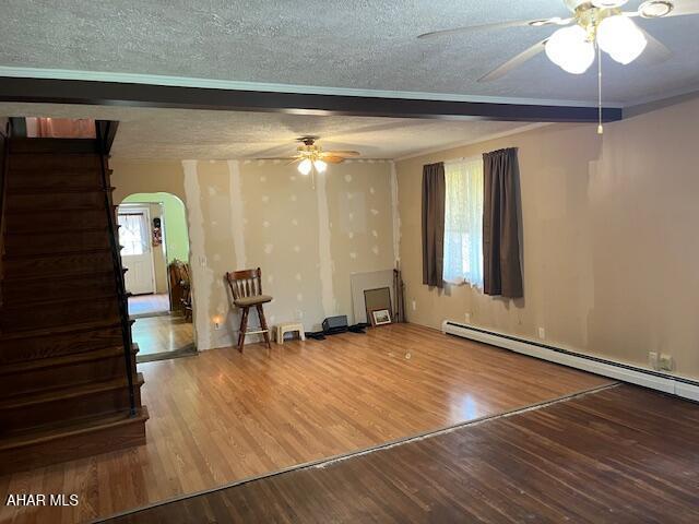 6331 Hyndaman Rd, Buffalo Mills, PA 15534 - unfurnished living room featuring a ceiling fan, arched walkways, stairs, wood finished floors, and a textured ceiling
