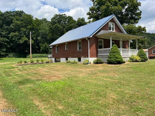 6331 Hyndaman Rd, Buffalo Mills, PA 15534 - view of front facade with brick siding, a front yard, covered porch, and an attached garage