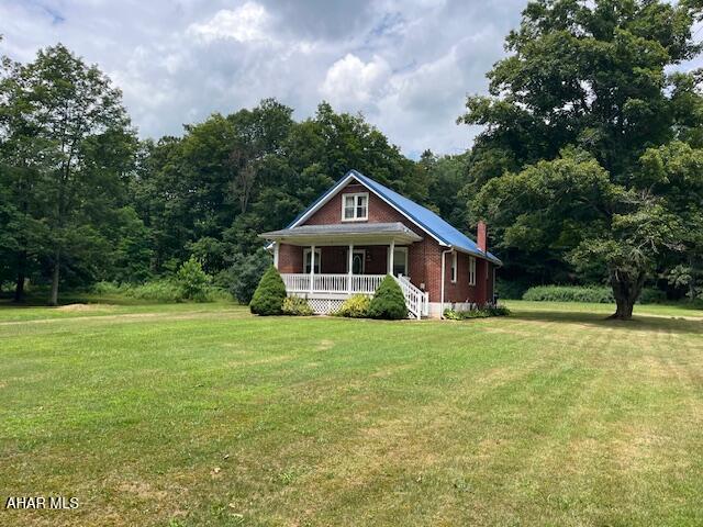 6331 Hyndaman Rd, Buffalo Mills, PA 15534 - view of front of property featuring covered porch, a front lawn, a chimney, and a forest view