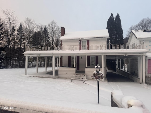 snow covered rear of property featuring a balcony