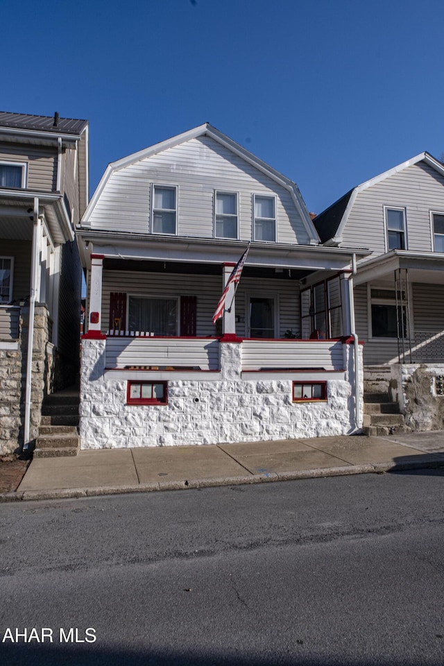 view of front facade featuring a gambrel roof and a porch