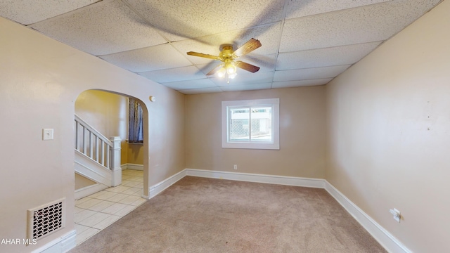 carpeted spare room featuring ceiling fan and a drop ceiling