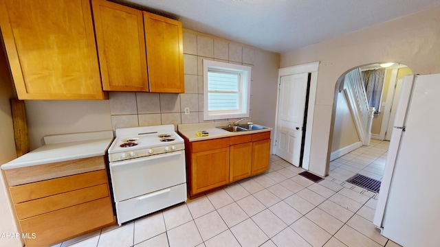 kitchen featuring sink, white appliances, light tile patterned floors, and tasteful backsplash