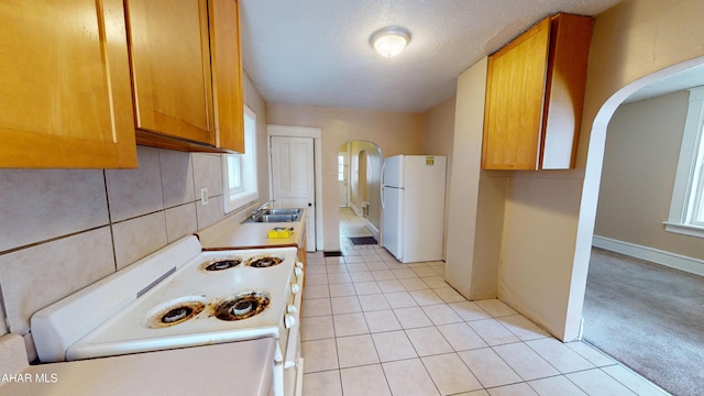 kitchen with a textured ceiling, sink, light colored carpet, and white appliances