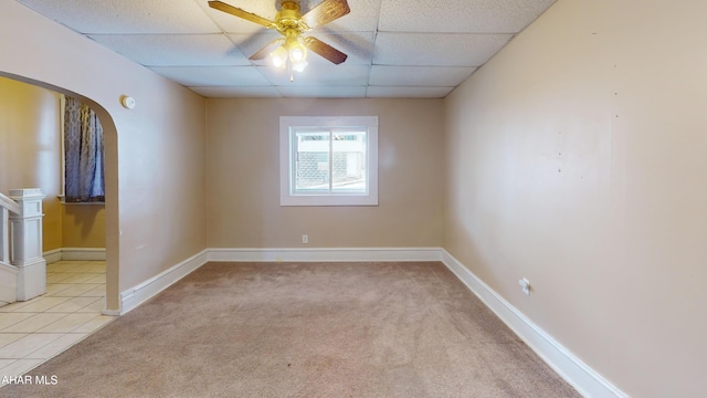 carpeted spare room with ceiling fan and a paneled ceiling