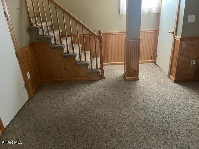 interior space with carpet flooring and wooden walls