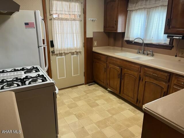 kitchen featuring sink, white appliances, and exhaust hood