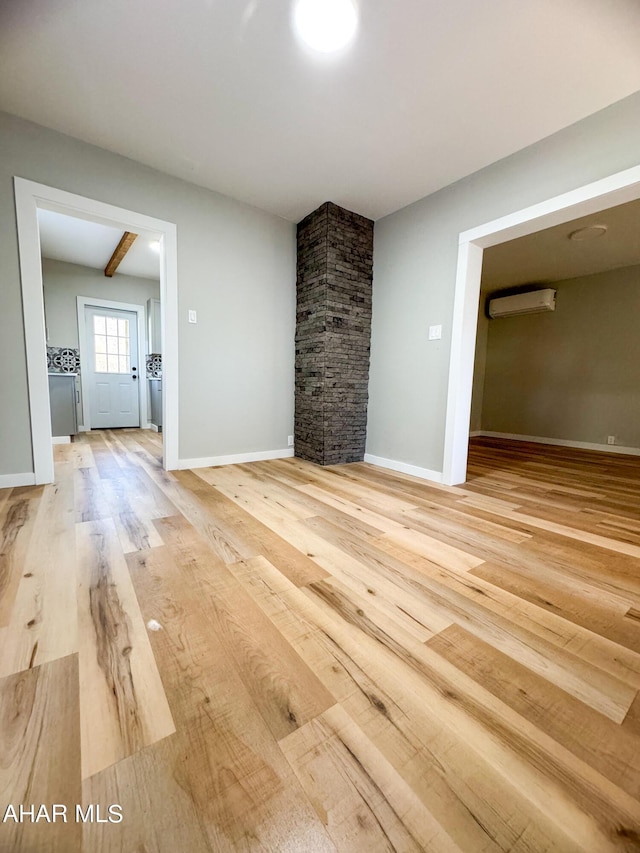 unfurnished living room with beamed ceiling, wood-type flooring, and an AC wall unit