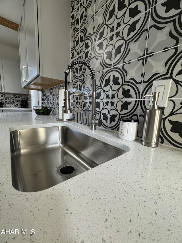 details with light stone counters, sink, and decorative backsplash